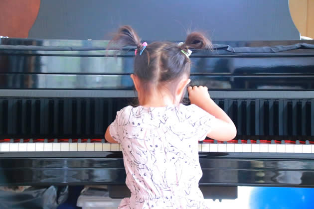 幼い女の子がピアノを演奏しているイメージ